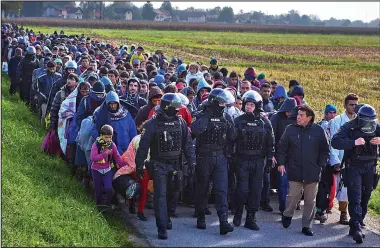  ??  ?? Chaos: A huge crowd of migrants is escorted by police as they cross from Croatia into Slovenia