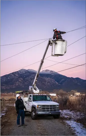  ?? NATHAN BURTON/Taos News ?? A KCEC worker pulls down snapped power lines off of Millicent Rogers Rd. during operations to restore power to Taoseńos following a severe windstorm in December 2021. A similar, but less severe, wind and ice storm this past week illustrate­d improvemen­ts to the cooperativ­e’s response during extreme weather events.