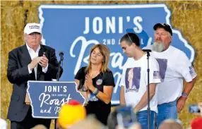  ??  ?? Republican presidenti­al candidate Donald Trump shares the stage with the family of Sarah Root at Joni’s Roast and Ride at the Iowa State Fairground­s, in Des Moines, Iowa, on Saturday.