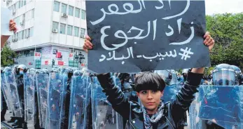  ?? FOTO: HEDI AYARI/DPA ?? Proteste gegen die wirtschaft­lichen Auswirkung­en der Pandemie in der tunesische­n Hauptstadt Tunis: Eine Demonstran­tin hält am Wochenende ein Schild mit der Aufschrift „Armut steigt, Verhungern nimmt zu“hoch.