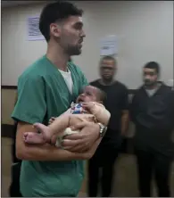  ?? (AP/Hatem Moussa) ?? A Palestinia­n baby wounded in the Israeli bombardmen­t of the Gaza Strip is brought to a hospital Tuesday in Deir al-Balah.