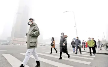  ??  ?? File photo shows a man wearing a respirator­y protection mask walking towards an office building during the smog after a red alert was issued for heavy air pollution in Beijing’s central business district, China. — Reuters photo