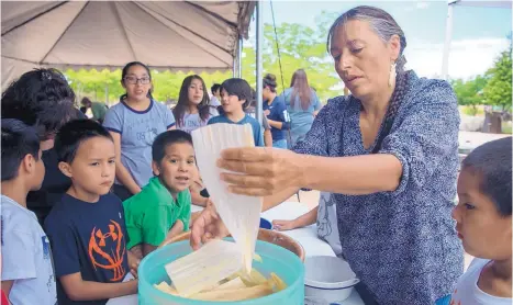  ?? EDDIE MOORE/JOURNAL ?? Roxanne Swentzell shows pueblo children from Tesuque and San Ildenfonso how to make tamales in July during a talk about eating precontact foods in Santa Fe.