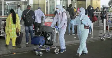  ??  ?? ↑
Passengers wearing personal protective equipment enter an airport in India.