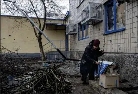  ?? AP PHOTO/ EVGENIY MALOLETKA ?? Emilia Budskaya, a local resident who decided to stay in the city breaks dead tree branches to heat her basement in the frontline city of Vuhledar, Ukraine, Saturday, Feb. 25, 2023.