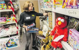  ??  ?? Volunteer Marina Meyers stocks Christmas toys at the Mustard Seed Street Church.