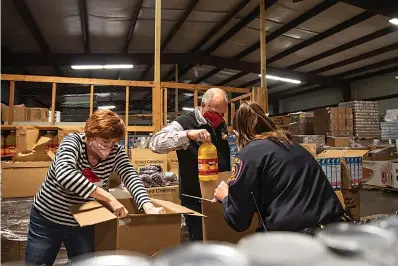  ?? Staff photo by Kelsi Brinkmeyer ?? ■ Texarkana, Arkansas city officials race against Texarkana, Texas city officials to pack the most boxes for Harvest Texarkana’s mobile pantry. The Texas-side team came out on top and were named the Harvest Hunger Hero Packing Champions.