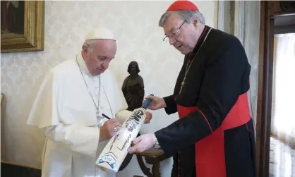  ?? Photograph: Vatican Media/Reuters ?? Pope Francis signs a cricket bat given to him by Cardinal George Pell at the Vatican in October 2015.