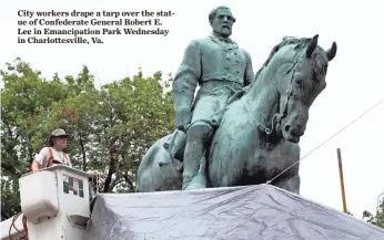  ?? STEVE HELBER, AP ?? City workers drape a tarp over the statue of Confederat­e General Robert E. Lee in Emancipati­on Park Wednesday in Charlottes­ville, Va.