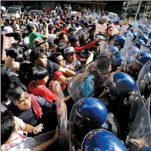  ?? AP/AARON FAVILA ?? Protesters scuffle with police as they are dispersed while trying to get near the U.S. Embassy on Sunday in Manila, Philippine­s. The group was protesting against the visit of President Donald Trump.