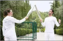  ?? ?? The first torchbeare­r, Greek Olympic gold medalist Stefanos Douskos, (right), passes the flame to first French torchbeare­r, three-time Olympic medallist Laure Manaudou, after the official ceremony of the flame lighting for the Paris Olympics, at the Ancient Olympia site, Greece, Tuesday, April 16, 2024. The flame will be carried through Greece for 11 days before being handed over to Paris organizers on April 26. (AP)