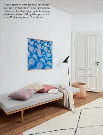  ??  ?? Det blå tekstilvae­rk fra Sakura Copenhagen lyser op over daybedden fra Design Classic. Puderne er fra Eline Engen og Stilleben og plaiden fra Aiayu. ‘Aj’-gulvlampen er fra Louis Poulsen og kurven fra Lillerød.