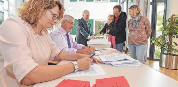  ?? FOTO: BERND BAUR ?? Eintragen, wählen, Stimmzette­l in die Urne: Hochbetrie­b im Wahllokal in Schwendi.