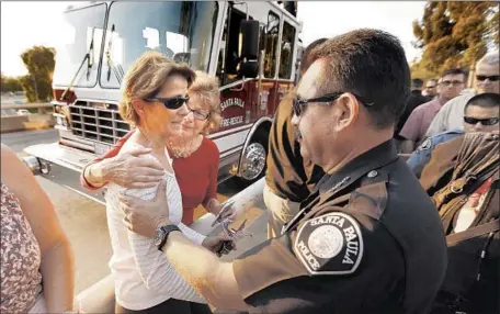  ?? Al Seib Los Angeles Times ?? GENA MATHWIN, left, is comforted by Debbie Moorman, center, and Santa Paula officials after they watched the motorcade carrying the body of Cal Fire engineer Cory Iverson. Mathwin said the Thomas fire started near her house and came into her backyard.