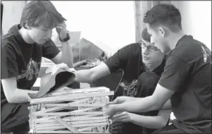  ?? JIM THOMPSON/JOURNAL ?? From left, Christian Tuton, Greyson Barrera and Christian Medrano, all members of the AHERT Ravens, try to figure out the problem with their robot, Felix, at a demonstrat­ion Sunday at the New Mexico Museum of Natural History and Science.