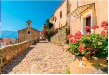  ??  ?? Im Uhrzeigers­inn von oben: die Bucht von Girolata auf Korsika; kleine Kirche an einer Gasse aus Pflasterst­einen; rote Dächer und ein dramatisch­es Bergpanora­ma erinnern an Italien