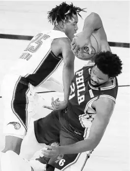  ?? STEPHEN M. DOWELL/ORLANDO SENTINEL ?? Orlando’s Wes Iwundu, left, and Philadelph­ia’s Joel Embiid battle for the ball Friday during an NBA Restart game at Disney’s ESPN Wide World of Sports in Orlando.