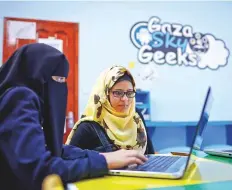  ?? Bloomberg ?? A tech freelancer, right, watches as a female trainee works on a laptop at the offices of Gaza Sky Geeks in Gaza City. Gaza Sky Geeks helps its graduates get paid for their work.