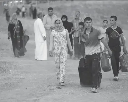  ??  HUSSEIN MALLA/THE ASSOCIATED PRESS FILES ?? Fleeing Iraqi citizens from Mosul and other northern towns walk toward a Kurdish security forces checkpoint in has tightened restrictio­ns to prevent residents from leaving the city.
northern Iraq. The Islamic State group