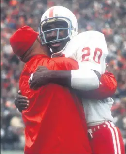  ?? LINCOLN JOURNAL STAR VIA AP, FILE ?? Nebraska’s Johnny Rodgers (20) hugs an assistant coach on the sideline after his punt return for a touchdown against Oklahoma in their 1971“Game of the Century.”