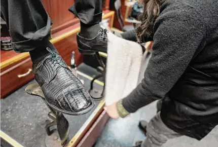  ?? Mary Altaffer/Associated Press photos ?? Bertha Gomez shines a customer’s shoes at the Alpha Shoe Repair Corp. on Feb. 3 in New York. Once a common practice, the tradition of getting a quick polish from a rag-toting shoeshine has become more of a rarity, and many stands have disappeare­d across the country.