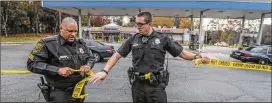  ?? JOHN SPINK / JSPINK@AJC.COM 2017 ?? DeKalb Couny Police Sgt. A.A. Coachman (left) and Officer Donald Warney tape off a crime scene outside a gas station last November . The DeKalb force has recorded an impressive closing rate for homicides so far this year, an achievemen­t that has been credited to more staff and good community relationsh­ips.