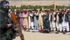  ?? Mohsen Karimi/AFP via Getty Images ?? A Taliban security guard oversees Afghan Muslim devotees offering prayers for Ramadan on Friday. Afghanista­n’s forces targeted Pakistani military posts along the border Monday in the first known Taliban counteratt­ack since they took power.