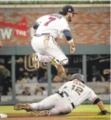  ?? JOHN AMIS/ASSOCIATED PRESS ?? Braves shortstop Dansby Swanson, top, throws to first after forcing out Giants’ Joe Panik during the first inning of Tuesday’s game in Atlanta.