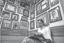  ??  ?? Melody Poe reads below autographe­d photos as she waits for her party at Charles Cavallo’s Cupboard Restaurant. Coming from the produce business, Cavallo has added more fresh vegetables to the menu.