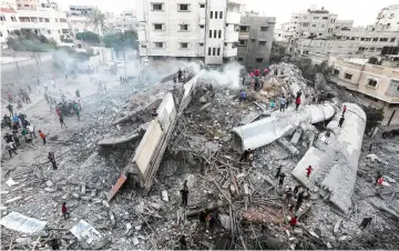  ??  ?? Photo shows people inspecting the rubble of a building following an Israeli air strike on Gaza City. — AFP photo