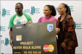  ?? Photo: Paheja Siririka ?? Walk on… Tim Ekandjo, getting the pledge on behalf of Project Never Walk Alone from Standard Bank Namibia’s CEO Mercia Geises and head of marketing Magreth Mengo.