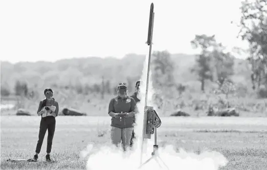  ?? STACEY WESCOTT/CHICAGO TRIBUNE PHOTOS ?? Lilly Abney, from left, 13, Rebecca Zurek, 17, and Luka Weideman, 14, all members of the Redhawk Rocketeers from Prince of Peace Catholic School in Lake Villa, watch their rocket launch while practicing Wednesday for The American Rocketry Challenge competitio­n. Naperville’s Neuqua Valley High School is also competing.