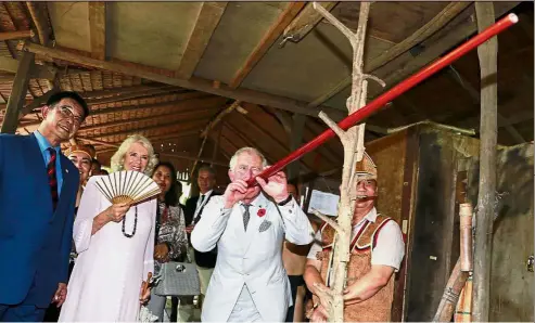  ??  ?? Getting a good aim: Prince Charles shooting a blowpipe during a visit to the Sarawak Cultural Village while Camilla and State Tourism Minister Datuk Abdul Karim Rahman Hamzah (left) look on.