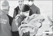  ??  ?? A RED CROSS volunteer holds a baby in Porto Empedocle, Sicily, after the arrival of rescued migrants.