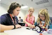  ?? Jerry Baker ?? Camp aide Rene Schulze, left, a sophomore at Texas A&M, joins campers Gabby Martin and Ashley Pickering for work on a Lego project.