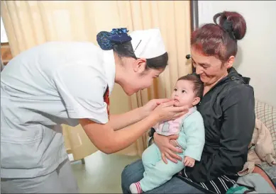  ?? CAI YANG / XINHUA ?? A nurse from the Hospital of Xinjiang Traditiona­l Uyghur Medicine, attends to a mother from Uzbekistan, along with her daughter, who was born in the facility in Urumqi, capital of the Xinjiang Uygur autonomous region.