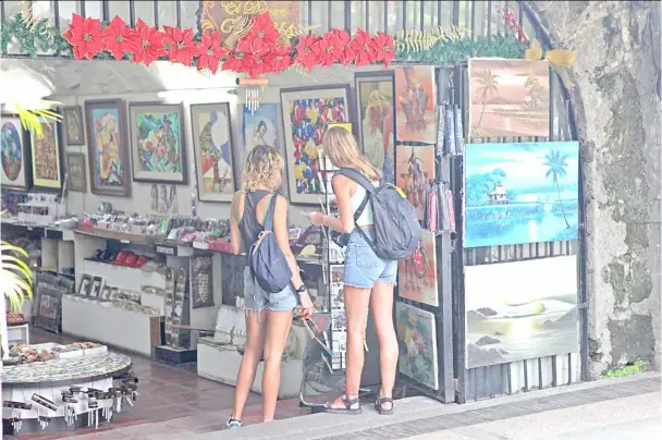  ?? PHOTOGRAPH BY JOEY SANCHEZ MENDOZA FOR THE DAILY TRIBUNE @tribunephl_joey ?? RUSSIAN tourists browse a postcard display shelf in a souvenir shop at Fort Santiago inside the walled city of Intramuros, Manila Sunday. The comely young women could have been, themselves, the subjects of the artworks also on sale.