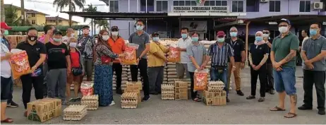  ??  ?? Lau (centre) presents the donated rations to a recipient during the event at the flats.