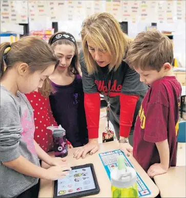  ?? Anthony Souffle Chicago Tribune ?? ANDREW ZHU, right, shares his iPad to help classmates with a lesson at Walden Elementary School in Deerfield, Ill. The American Academy of Pediatrics says such devices have limited educationa­l value before age 2.