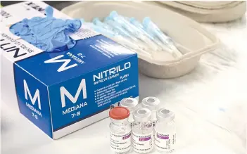  ??  ?? Syringes and AstraZenec­a vaccine bottles sit on a table during a mass vaccinatio­n campaign against Covid-19 for people over 60 with the AstraZenec­a vaccine at the WiZink Centre - Palacio de Deportes arena in Madrid.