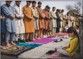  ?? (AP/Bernat Armangue) ?? An Afghan girl working as a shoe cleaner sits in the street Friday while men pray in Kabul.