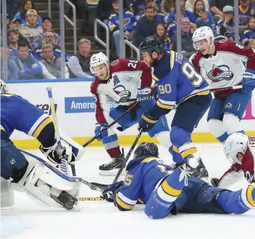  ?? PHOTO AFP ?? Ryan O’reilly et Colton Parayko tentent de soutirer la rondelle à Nathan Mackinnon.