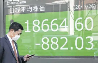  ?? FOTO: DPA ?? Ein Passant in Tokio vor einer Anzeigetaf­el mit dem Aktienkurs des Nikkei-225-Index: Die Angstbarom­eter der Börsen registrier­en in diesen Tagen eine hohe Nervosität auf den internatio­nalen Finanzmärk­ten.