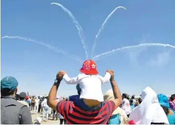  ?? — AFP ?? People watch the British Aerobatics team Yakovlevs perform on the fourth day of the five-day Aero India 2019 Airshow at the Yelahanka Air Force Station in Bangalore on Saturday.