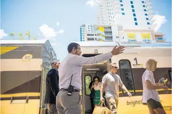  ?? YUTAO CHEN/STAFF PHOTOGRAPH­ER ?? Assistant station manager Marcus Ramirez guides passengers from Miami arriving at the downtown West Palm Beach station. Park-Line Palm Beaches, a 24-story apartment building overlookin­g the train station, is set to open in the fall.