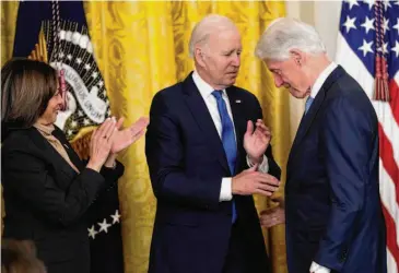  ?? Susan Walsh/Associated Press ?? President Joe Biden greets former President Bill Clinton as Vice President Kamala Harris applauds at an event to mark the 30th anniversar­y of the Family and Medical Leave Act.