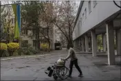  ?? BERNAT ARMANGUE — THE ASSOCIATED PRESS ?? A man uses a wheelchair to transport water to a hospital in Kherson, southern Ukraine, on Friday.