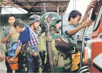  ?? — Reuters photo ?? Government soldiers help two boys board a public vehicle along with twenty other residents who were rescued as the government troops continue to assault the Maute group in Marawi city, Philippine­s.