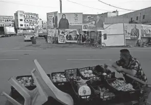  ?? HADI MIZBAN/AP ?? A street vendor in Baghdad who sells fruits passes by campaign posters for Sunday’s parliament­ary elections in Iraq.