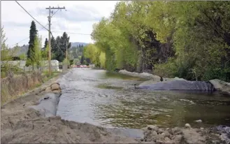  ?? SUSAN McIVER/Special to The Okanagan Weekend ?? Aeneas Creek in Summerland has breached its banks, and municipal crews have erected berms and tiger dams to control the rising water and prevent it from flooding the centre of town. This photo was taken looking south down Garnet Avenue at the corner...